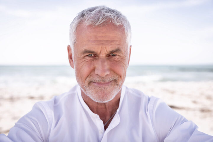 Portrait Headshot älterer Mann mit weissem Hemd am Strand